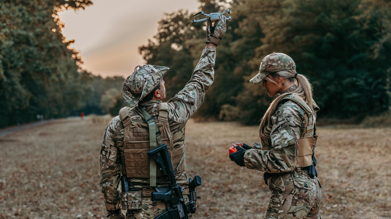Ein Soldat hält eine Drohne hoch, während ein anderer einen Controller dafür hält