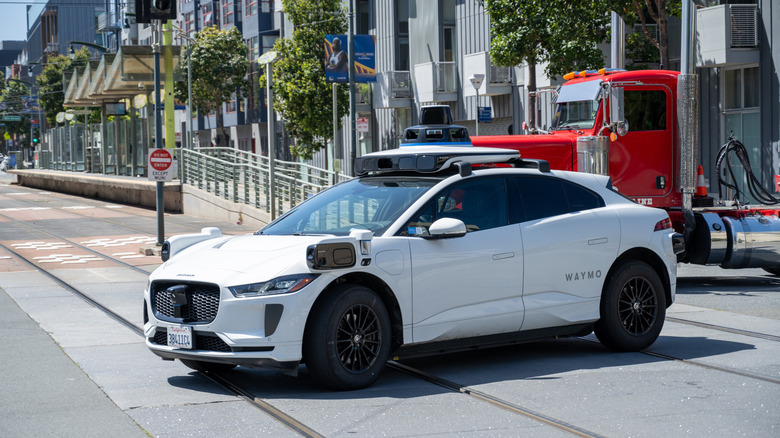 Ein weißer Jaguar I-Pace Waymo überquert Stadtbahngleise in San Francisco.