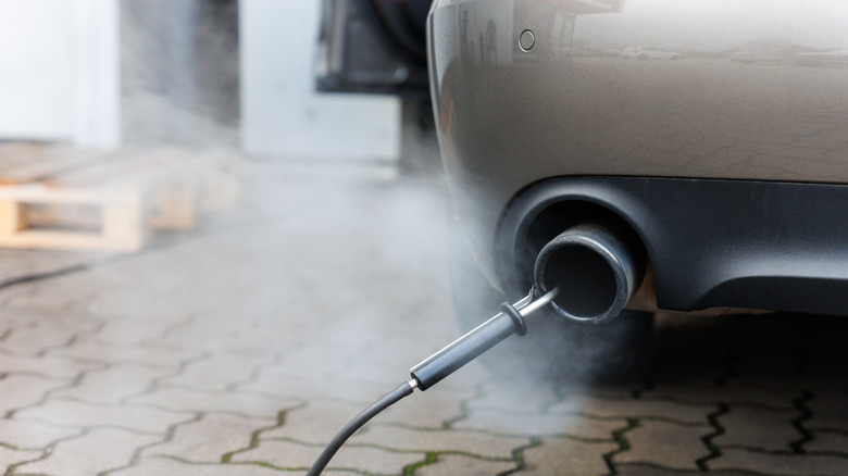 Nahaufnahme eines Abgasrohrs mit daran befestigtem Sensor während einer Abgasuntersuchung