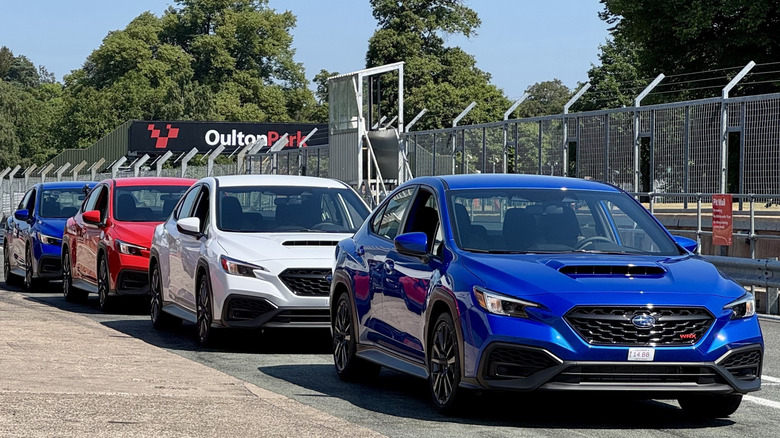 Ein Foto von vier rot-weiß-blauen WRXs, die an der Box im Oulton Park geparkt sind