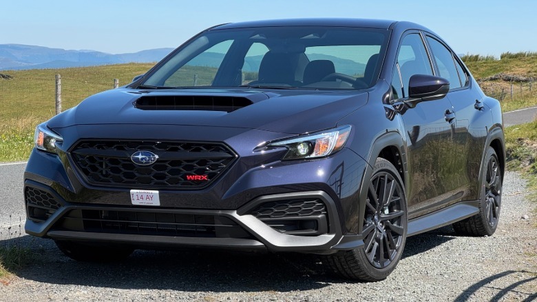 Eine Dreiviertelaufnahme von vorne eines Galaxy Purple Pearl WRX, der an einem klaren Tag auf Schotter neben einer Straße und Gras geparkt ist