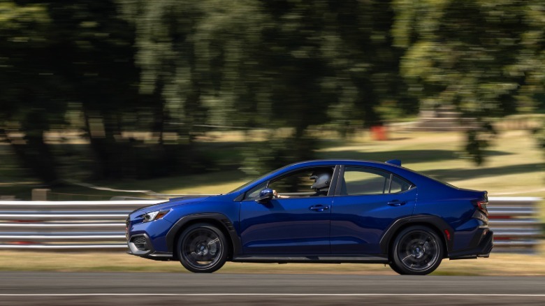 Eine Seitenansicht eines blauen WRX, der im Oulton Park an Bäumen vorbeifährt