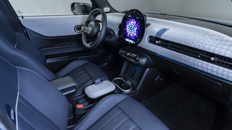 Blick durch das Beifahrerfenster eines Mini Cooper mit blauem Innenraum und hellem Armaturenbrett