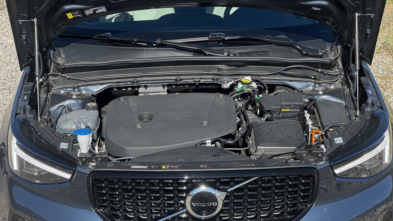 Eine Unterfahraufnahme des blauen XC40, der mit eingeschalteten Tagfahrlichtern auf Schotter geparkt ist