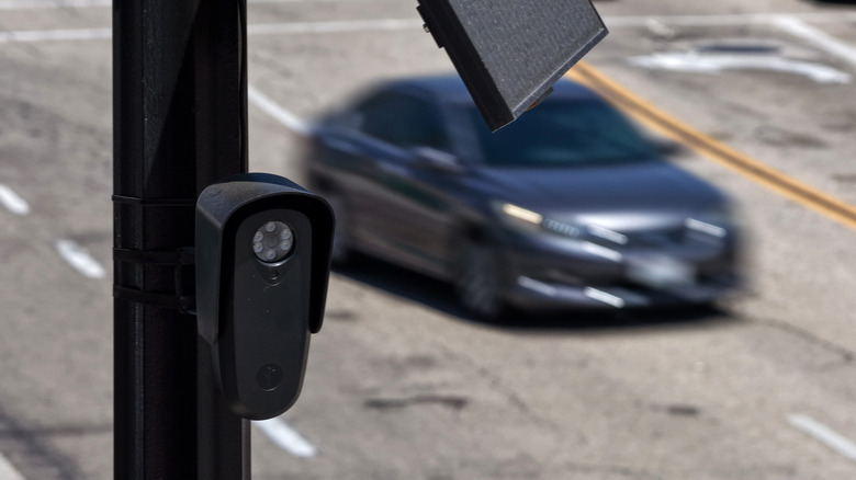 Eine Flock-Kamera an einem Mast über einer Straße, während ein Auto vorbeifährt