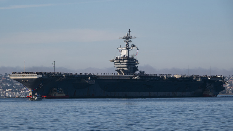 SAN DIEGO, KALIFORNIEN – 20. DEZEMBER: Matrosen und Marineinfanteristen bewachen die Schiene, während der Flugzeugträger der Nimitz-Klasse der US-Marine, USS Abraham Lincoln (CVN 72), von Schleppern in der Bucht von San Diego gesteuert wird, als er nach einem fünfmonatigen Einsatz im Nahen Osten am 20. Dezember 2024 in San Diego, Kalifornien, zu seinem Heimathafen Naval Air Station North Island zurückkehrt. (Foto von Kevin Carter/Getty Images)