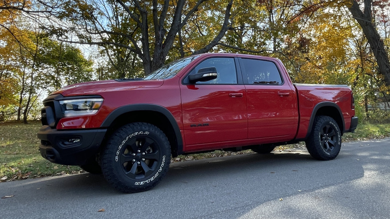 Ein roter 2023 Dodge Ram 1500 Rebel auf einer Seitenstraße mit umgestürzten Bäumen dahinter.