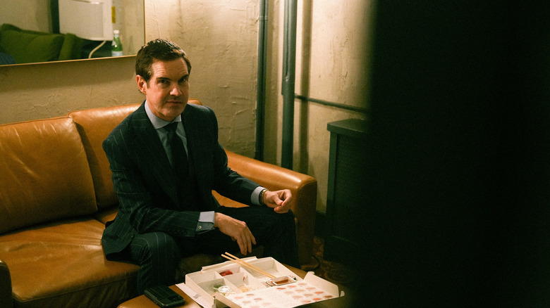Jimmy Carr sitzt auf einer Couch und isst Sushi