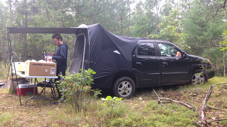 Der schwarze Pontiac Aztek Baujahr 2002 im Wald mit Zeltzubehör im Einsatz.