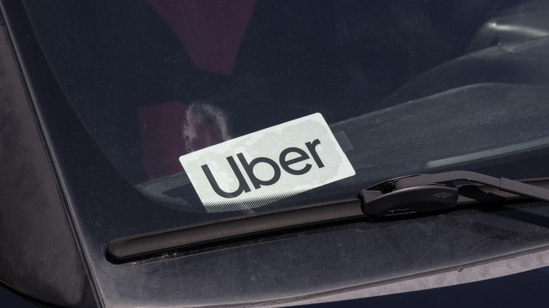 In der Windschutzscheibe eines Mitfahrautos hängt ein Uber-Schild.