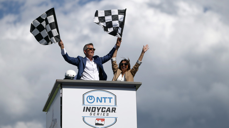 Sean Duffy, US-Verkehrsminister, steht auf der Start-/Zieltribüne beim Freedom 250 IndyCar-Rennen in Washington DC im Jahr 2026 und schwenkt die Zielflaggen.