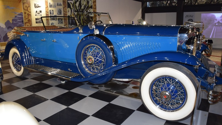 Ein blaues Duesenberg Model J von 1931 parkte auf einem Schachbrettboden in einem Automuseum