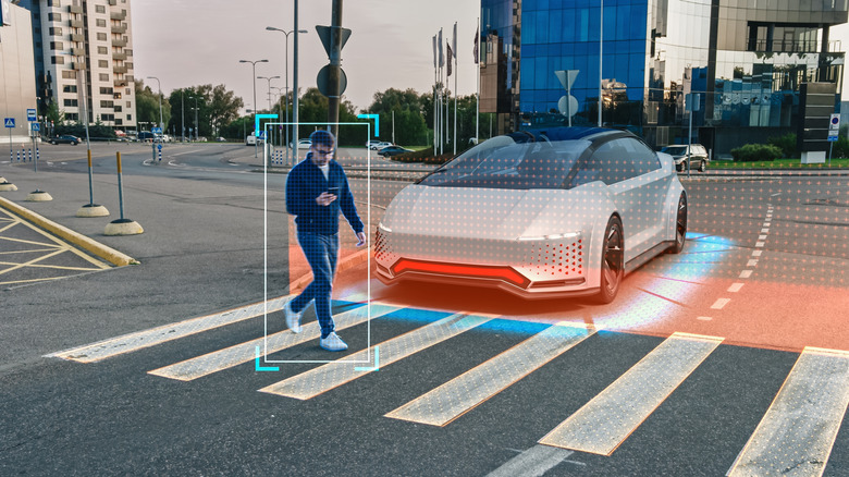 Eine 3D-Darstellung eines autonomen Fahrzeugs, das sich einem Zebrastreifen in einem Stadtgebiet nähert und vor einem Mann anhält, der über den Weg läuft und auf sein Handy schaut.