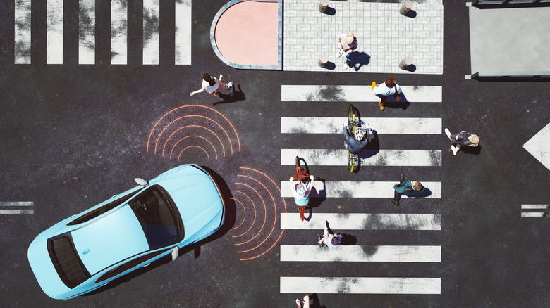 Ein autonomes Fahrzeug nähert sich einer komplexen Kreuzung, während Menschen auf Fahrrädern unterwegs sind.