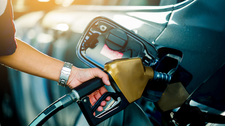 Eine Person, die Gas mit einer Düse pumpt.