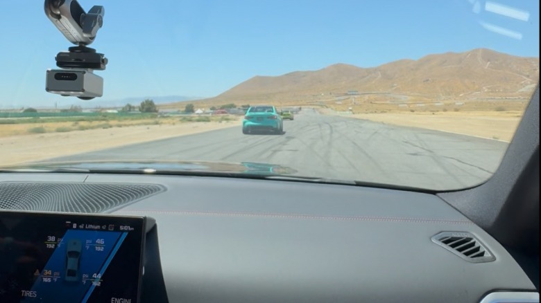 Ein Foto aus der Perspektive des Beifahrers im M3, wie er direkt auf die Gerade einfährt und einem türkisfarbenen M3 folgt