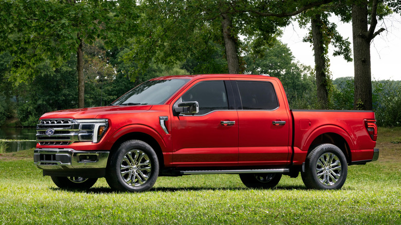 2027 Ford F-150 Lariat Seitenprofil auf Gras vor Bäumen geparkt