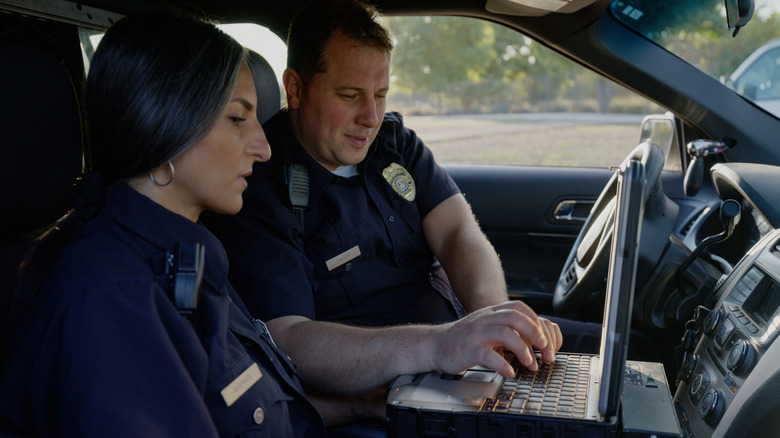 Archivbild von zwei Polizisten auf einem Laptop in ihrem Auto.