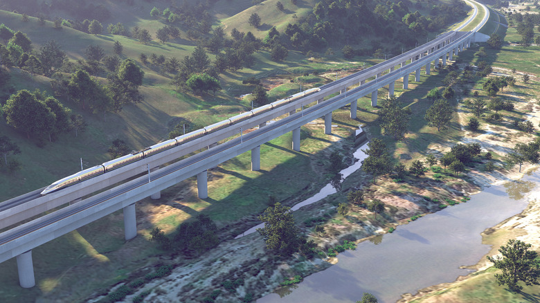 Overhead-Darstellung des CA-Hochgeschwindigkeitszuges, der sich auf einer erhöhten Brücke durch eine natürliche kalifornische Landschaft schlängelt