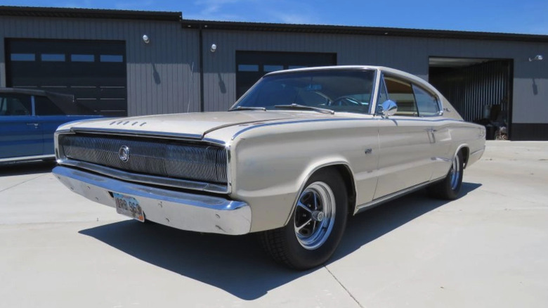 Ein weißer Dodge 426 Hemi Charger, Baujahr 1966, parkte auf Beton vor einer großen Garage.