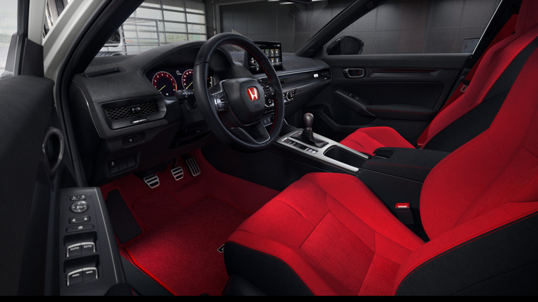 Ein Blick durch die Fahrertür auf das Armaturenbrett des 2027 Civic Type R mit seinen roten Sitzen und dem neuen Ultrasuede-Armaturenbrett