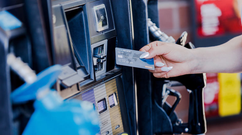 Stockbild einer Person, die mit einer Bankkarte für Benzin bezahlt.