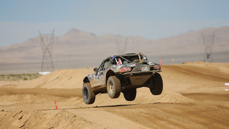 Das hintere Ende von Buddy, dem Offroad-Miata, als er auf einem sandigen Hügel auf einer Wüstenpiste landet
