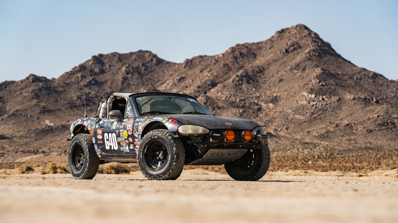 Buddy, der Offroad-Miata, der vor einem Wüstenberg geparkt ist