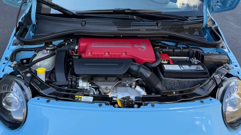 Ein Blick unter die Motorhaube des hellblauen Fiat zeigt die knallrote Motorabdeckung