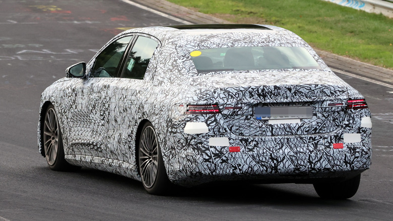 3/4-Rückansicht einer getarnten Mercedes E-Klasse EV auf dem Nürburgring