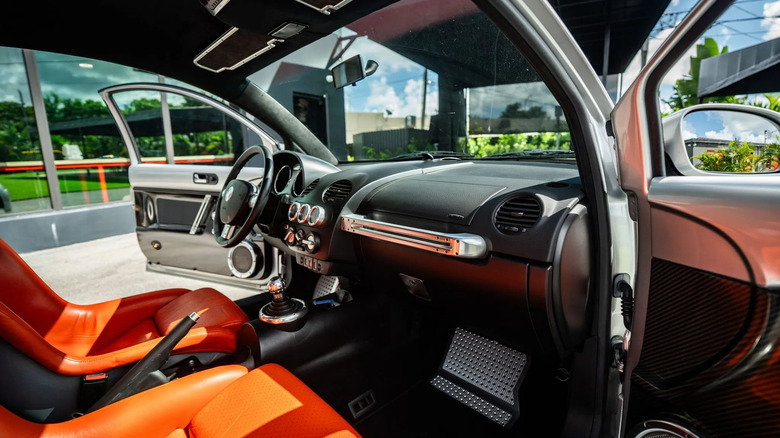 Ein Blick durch die Beifahrertür auf das makellose und schöne Interieur des Beetle RSi mit seinen orangefarbenen Sitzen und freiliegenden Carbon- und Aluminiumverkleidungen