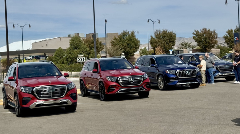 Weitwinkelaufnahme der Front von vier verschiedenen GLS-Modellen, die nebeneinander geparkt sind, mit zwei roten Standard-GLS auf der linken Seite, einem dunkelblauen GLS63 und einem dunklen GLS dahinter